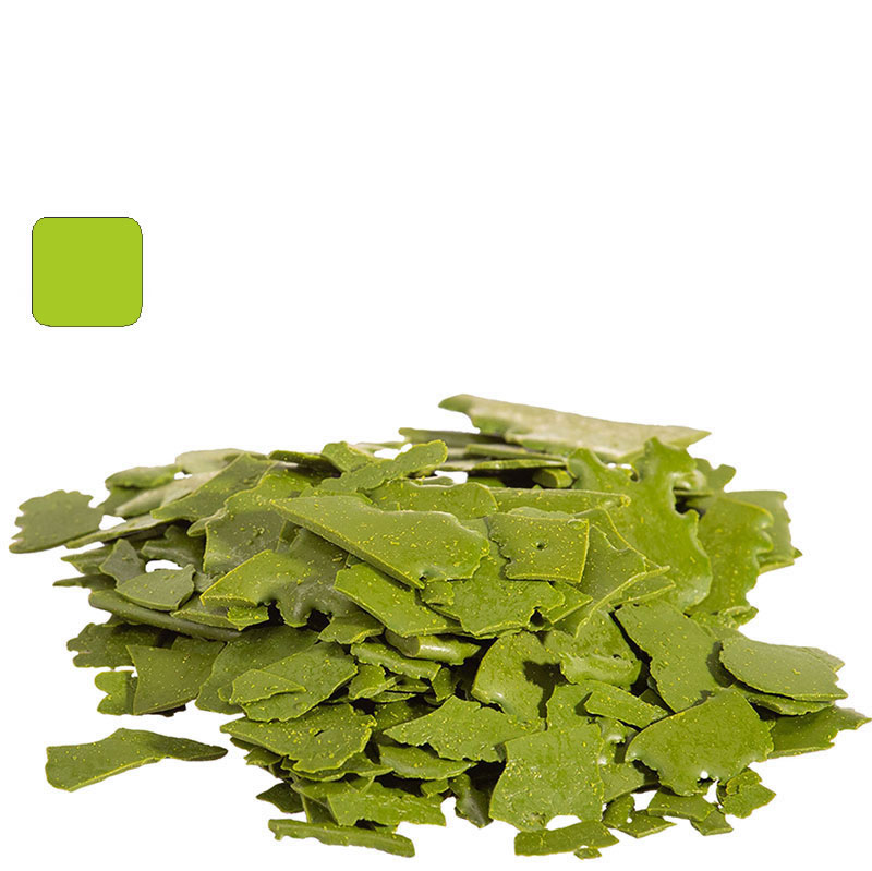 Pile of irregular bright green chocolate shavings on a white background, likely matcha-flavored.